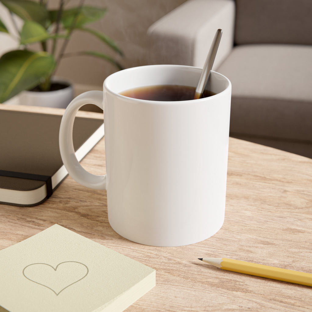 White mug with coffee on a wooden table with a notebook and pen in the background