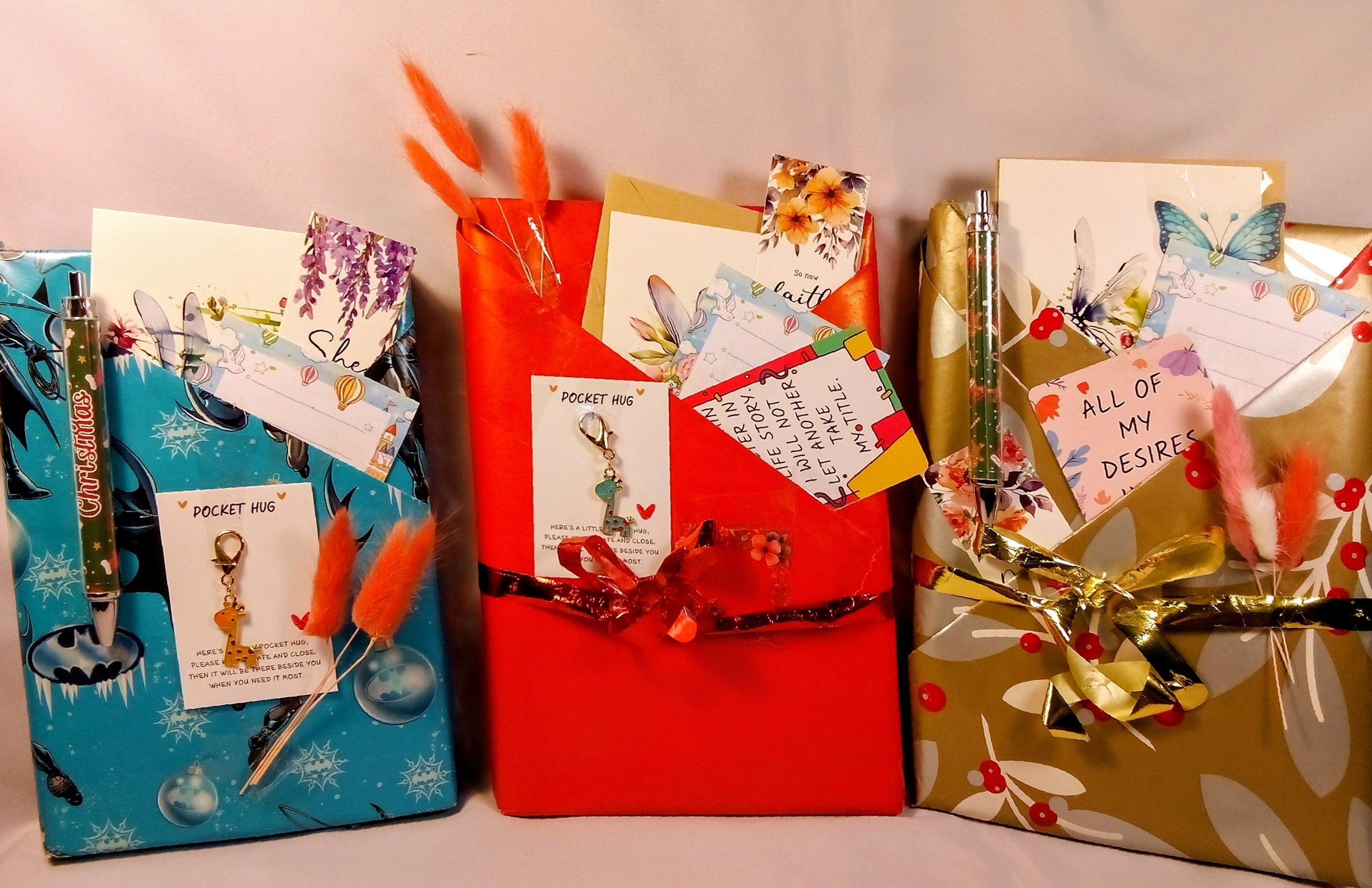 Three wrapped presents with decorative ribbons and cards on a neutral background